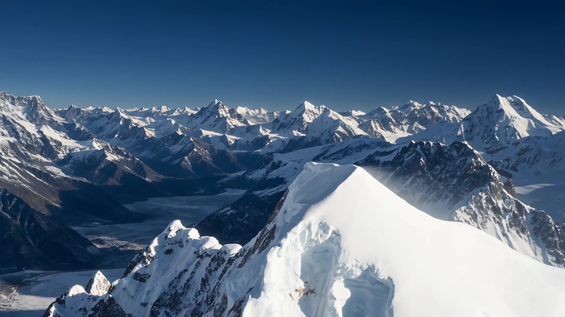 Snow-covered summit ridge under a deep blue sky